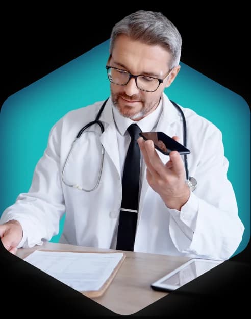 Physician at a desk reviewing a claims worksheet while following up on an unpaid account by phone