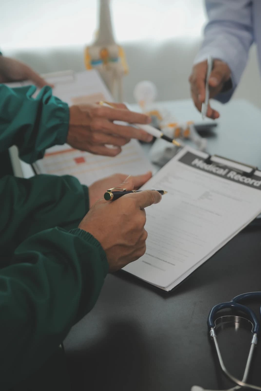 Clinician's hands holding a pen over a medical record on a clipboard