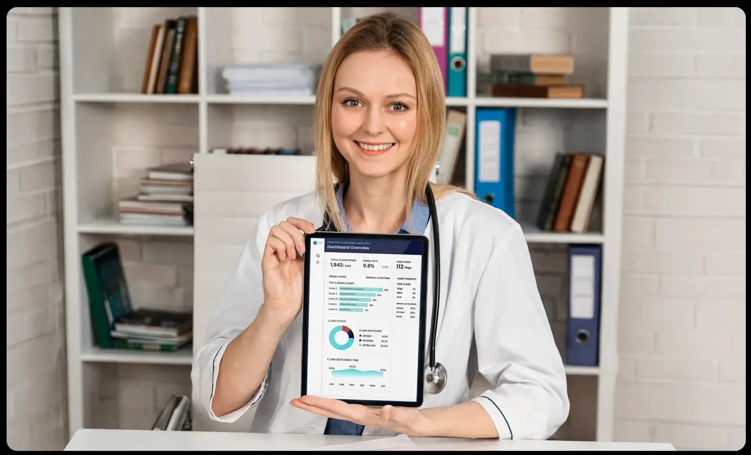 Pediatric billing specialist holding a tablet showing a claim denial analytics dashboard