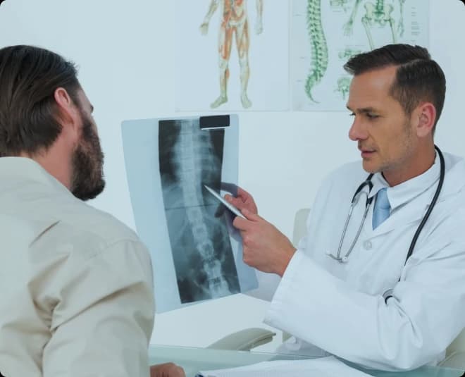 Clinician reviewing a spinal X-ray with a patient during a trauma follow-up