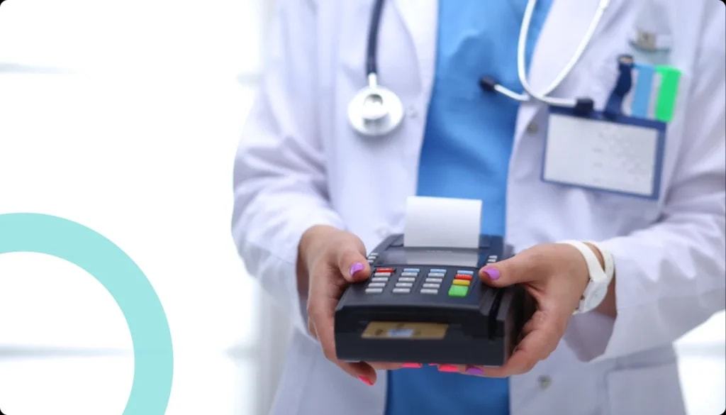 Clinician in a white coat holding out a card payment terminal printing a receipt