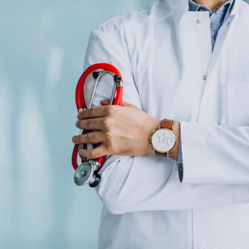 Physician in a white coat holding a stethoscope, arms folded