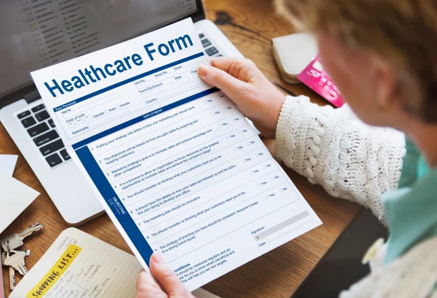 Healthcare insurance application form on a clipboard with a pen resting on it