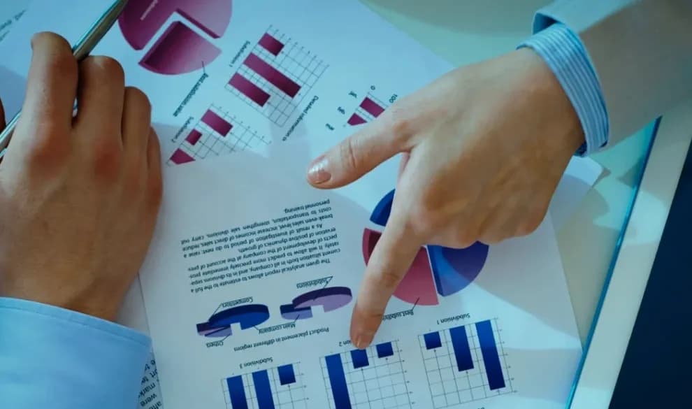 Two cardiology billing specialists reviewing a printed revenue analytics report