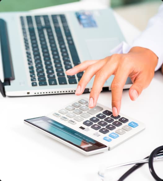 Billing expert working a calculator beside a laptop