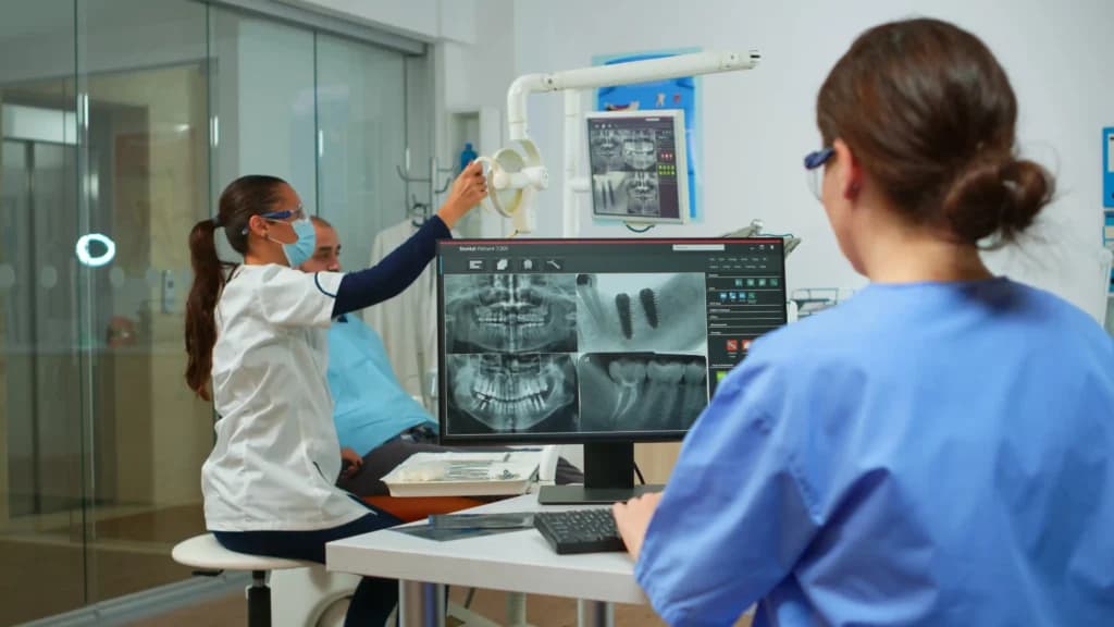 Dental x-ray on a monitor beside a patient's insurance paperwork